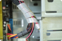 Close-up of computer case wiring bundled with white spiral cable wrap sleeve